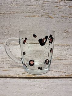 a glass cup with black and white spots on it sitting on top of a wooden table