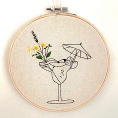 a cross stitch pattern with a cocktail glass and an umbrella on the side, in front of a white wall