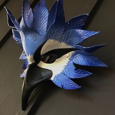 a blue and white mask with large leaves on it's face sitting on a table