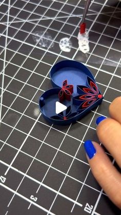 a person holding a blue object on top of a cutting board with scissors and tape