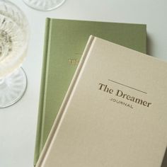 two books sitting next to each other on top of a white table with wine glasses