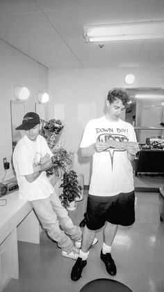 two men standing in a room with plants