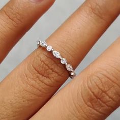 a woman's hand with a diamond ring on her left finger and the other half of her wedding band