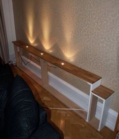 a long wooden shelf sitting on top of a hard wood floor next to a wall