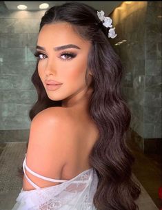 a woman with long dark hair and flowers in her hair, wearing a white dress