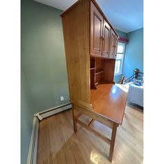 an empty room with wooden floors and cabinets in the corner, including a desk that has been turned into a bookcase