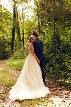 a bride and groom are standing in the woods