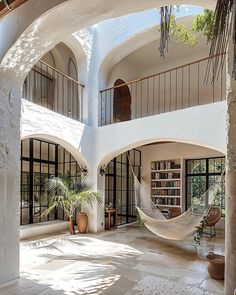 a hammock hanging in the middle of a room with large windows and doors