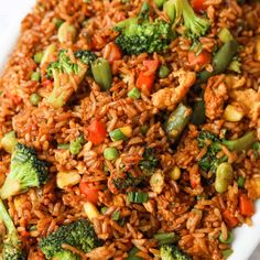 rice and vegetables are mixed together in a white dish on a table top, ready to be eaten