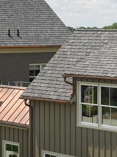 two houses with metal roofing and one has a bird perched on the shingles