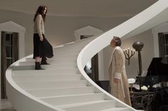 two women are standing on the stairs in a living room and looking at each other