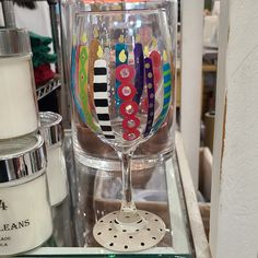 a close up of a wine glass on a table with candles and other items in the background