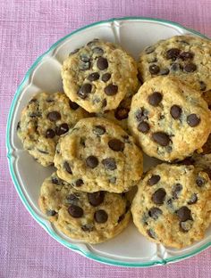 a plate full of chocolate chip cookies on a pink tablecloth with a purple cloth