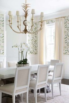 a dining room table with white chairs and a chandelier