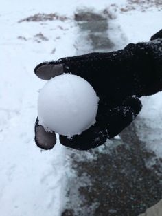 a person holding a snowball in their hand on a snowy street with no one around