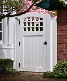 a white gate with an arched window and brick walkway