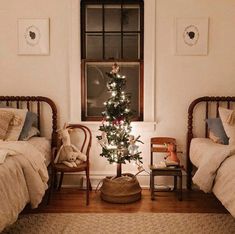 a small christmas tree in the corner of a room with two twin beds and a rug