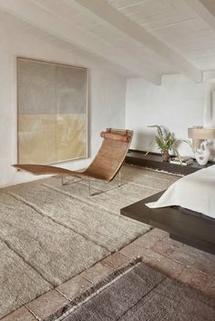 a bed room with a neatly made bed and a large rug on the floor in front of it