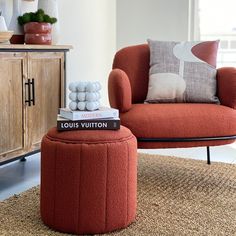 an orange chair and ottoman in a living room with a book on the footstool