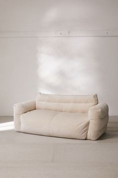 a white couch sitting on top of a hard wood floor next to a window in an empty room