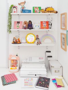 a white shelf filled with lots of toys and books on top of a table next to other items