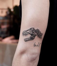 a close up of a person's arm with a tattoo on it that has a dinosaur