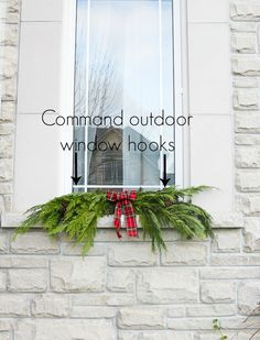 the window is decorated with evergreens and red bows, which are tied in twine