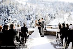 a bride and groom standing at the end of their wedding ceremony in front of snowy trees