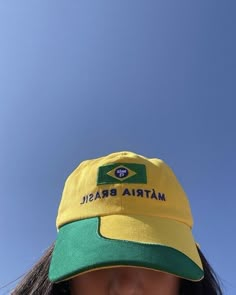 a woman wearing a yellow and green hat with the word matria brasil on it