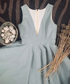 a blue dress and some dry grass on a carpet with eggs in a bowl next to it