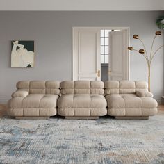 a living room with a large beige couch and blue rug on the floor in front of it