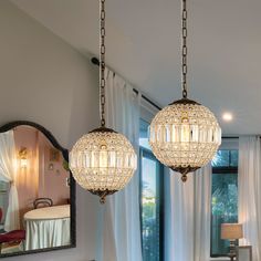 two chandeliers hanging from the ceiling in a living room next to a mirror