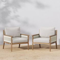 two chairs sitting next to each other in front of a white wall