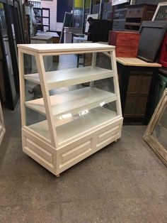 an empty glass display case sitting on the floor in a room filled with other items