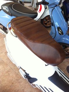 a motor scooter with a brown seat on the front is parked in a garage