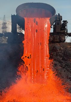 an orange fire hydrant spewing out water on top of a dirt hill