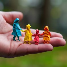 three origami people are standing in the palm of someone's hand