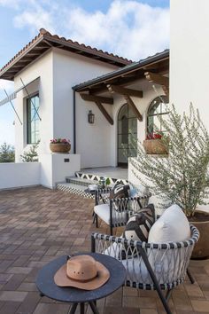 an outdoor patio with chairs, tables and potted plants on the side of it