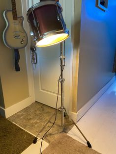 a drum on a tripod in front of a door with a guitar behind it