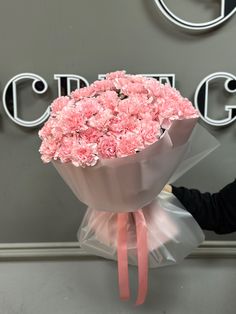 a bouquet of pink carnations wrapped in cellophane and tied with a ribbon