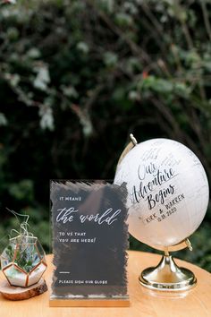 a table topped with a white ball next to a sign and a glass vase filled with flowers