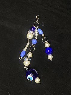 a blue and white beaded necklace on a black surface with beads hanging from it