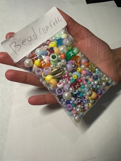 a hand holding a bag filled with lots of beads