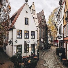 a cobblestone street in an old european town with white buildings and red tiled roofs