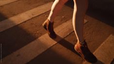 a woman's legs and shoes walking down the street at night with light shining on them