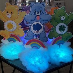 three teddy bears standing on top of a table with blue light up pom poms