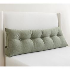 a close up of a bed with a pillow on top of it's headboard