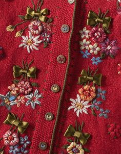 a red sweater with flowers and bows on the collar is seen in this close up photo