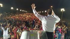 a man standing on top of a stage in front of a large group of people