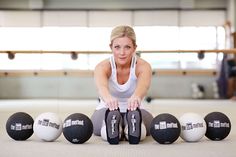 a woman is sitting on the floor with her feet up in front of five balls